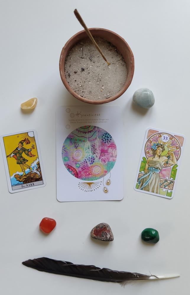 Tarot und Orakelkarten mit Steinen, Räucherstäbchen und Feder